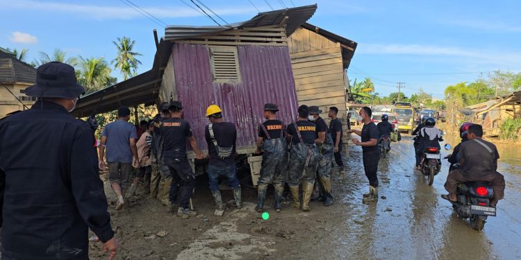 Bahu Membahu, Brimob Pindahkan Rumah Terseret Banjir yang Melintang di Jalan Nasional Tamiang–Langsa